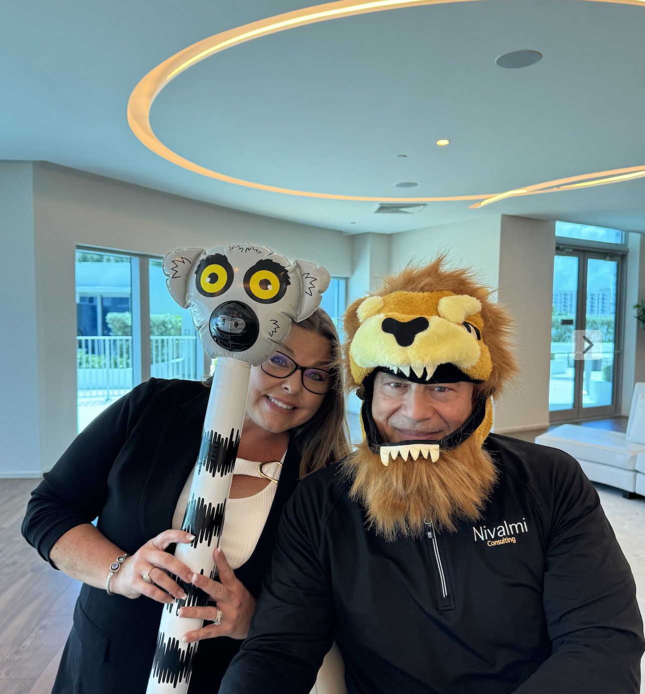 Darcy Blessing Williams holding an inflatable lemur beside a Nivalmi colleague wearing a lion hat at a Zookeeper session